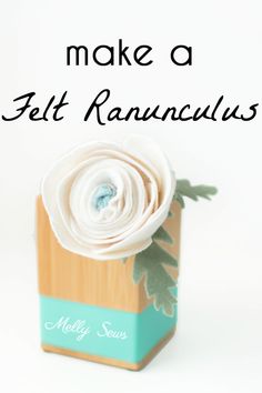 a white flower sitting on top of a wooden block with the words make a felt ranunculas