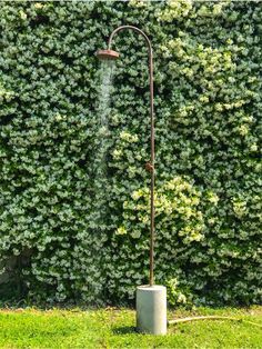 a water sprinkler in front of a green hedge