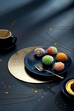 three desserts on blue plates with gold rimmed saucers and spoons next to each other