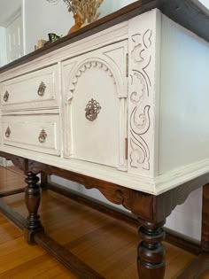 an old dresser is painted white and has ornate carvings on the top, along with wood flooring