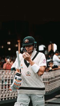 a man holding a baseball bat in his hand and wearing a helmet on top of it