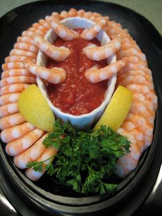 a black plate topped with shrimp and corn on the cob covered in ketchup