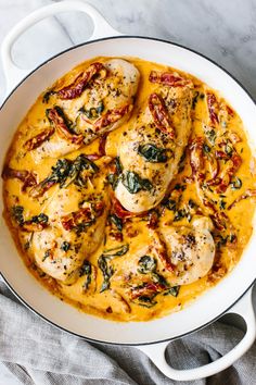 chicken with spinach and cheese in a white skillet on a marble countertop