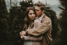 a man and woman embracing each other in front of christmas trees at the tree farm