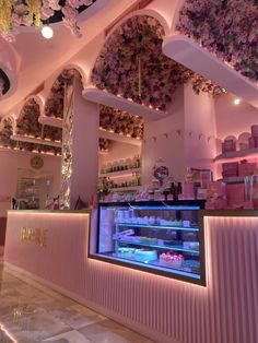 the interior of a pastry shop with pink flowers on the ceiling and lights above it