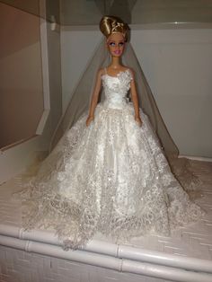 a barbie doll wearing a wedding dress and veil on top of a white shelf in a closet