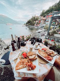 a table with food and drinks on it next to the water