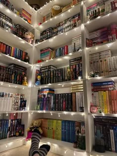 a person laying on the floor in front of a bookshelf filled with lots of books