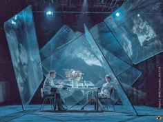 two people sitting at a table in front of large glass cubes with flowers on them