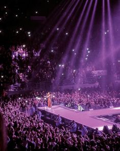 an audience at a concert with one person standing on a stage in front of the crowd