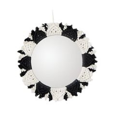 a round mirror with black and white crocheted trimmings on the edge