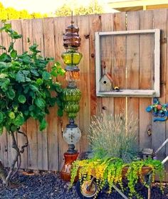 an outdoor garden with various plants and hanging items on the fenced in side yard