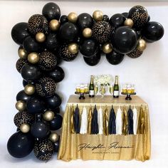 a table topped with black and gold balloons