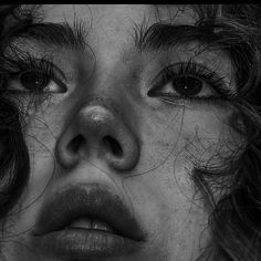 a black and white photo of a woman's face with hair blowing in the wind