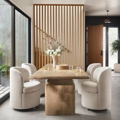 a dining room table surrounded by white chairs and wooden slatted walls with sliding glass doors