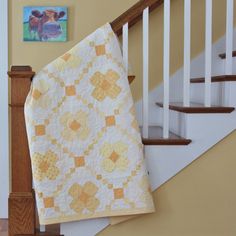 a quilt is hanging on the bannister next to a stair case and painting