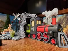 a fake train is on display in a museum setting with other decorations and paintings behind it