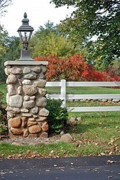 a stone pillar in front of a white fence