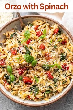 a bowl full of pasta with spinach and tomatoes