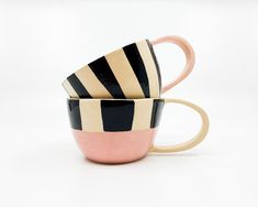 two coffee cups sitting side by side on top of each other in black and white stripes