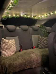 the interior of a car with christmas lights and decorations on the back wall, along with plush seats