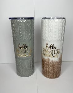 two silver and gold colored tumblers sitting next to each other on a white surface