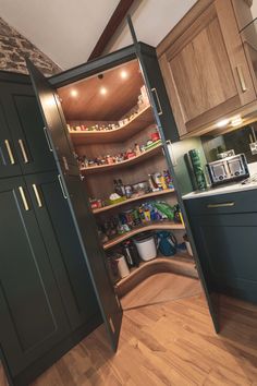 an open pantry in the middle of a kitchen with wooden flooring and green cabinets