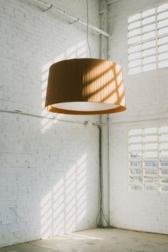 a lamp hanging from the ceiling in a room with white brick walls and flooring