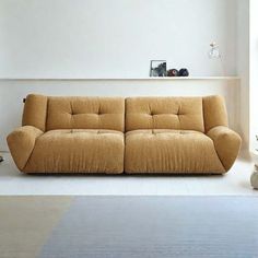 a brown couch sitting on top of a white floor in a living room next to a window