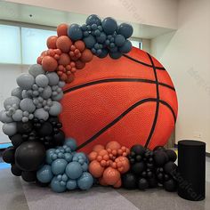 an inflatable basketball surrounded by black and orange balloons, stands on the floor