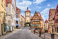 a cobblestone street in an old european town with tall buildings and clock towers