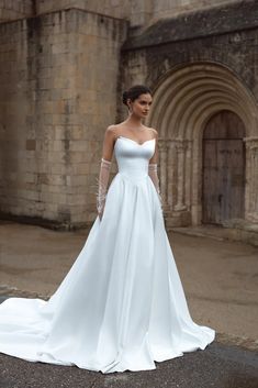 a woman in a white wedding dress standing outside