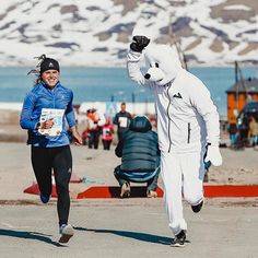 two people in costume running on the beach with snow covered mountains in the back ground