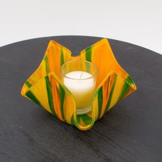 a glass candle holder sitting on top of a wooden table next to a white candle