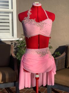 a pink and red dress on display in front of a house