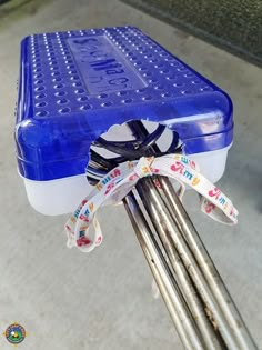 a blue and white cooler sitting on top of a metal pole with ribbons tied around it