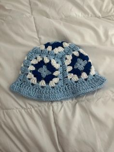 a blue and white crocheted hat laying on top of a bed