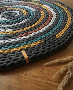 a round rug on the floor with different colored braiding around it and a tasseled rope