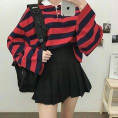 a woman taking a selfie with her cell phone wearing a red and black striped sweater