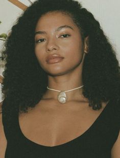 a woman with long hair wearing a choker and black tank top posing for the camera