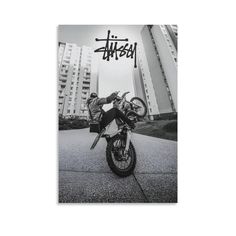 a black and white photo of a person on a motorcycle in front of tall buildings