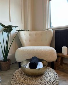 a living room with a chair, table and potted plant in the corner on the floor