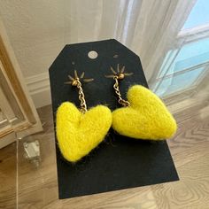 a pair of yellow heart shaped earrings sitting on top of a table