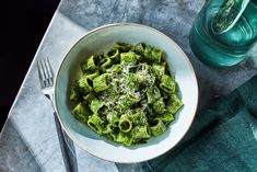 a white bowl filled with green pasta on top of a table