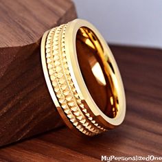 two gold rings sitting on top of a wooden table next to a piece of wood