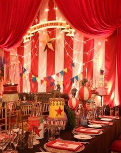 a table set up for a party with red drapes and decorations on the walls