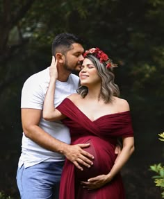 a pregnant woman wearing a flower crown standing next to a man