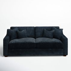 a blue couch with two pillows on the back and one pillow on the side, against a white wall