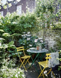 an outdoor table and chairs in the middle of a garden with plants growing on it