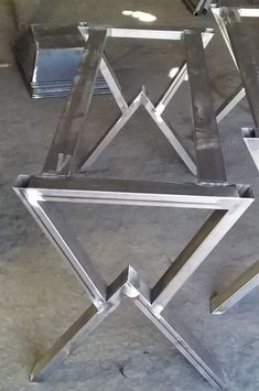 three glass tables sitting on top of each other in front of a metal structure with two legs